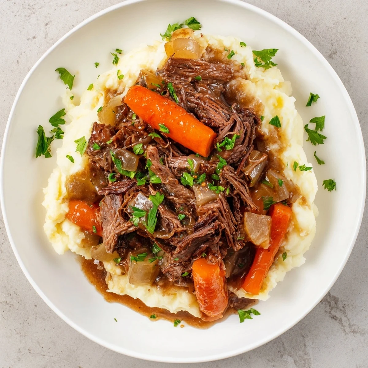 Hearty slow cooker pot roast: fork-tender beef and vegetables over a bed of fluffy mashed potatoes.