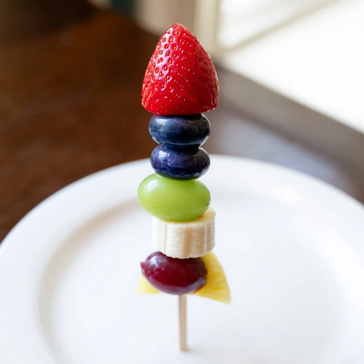 Vibrant Rocket Ship Fruit Skewers burst with color, a strawberry tip atop grapes and pineapple.