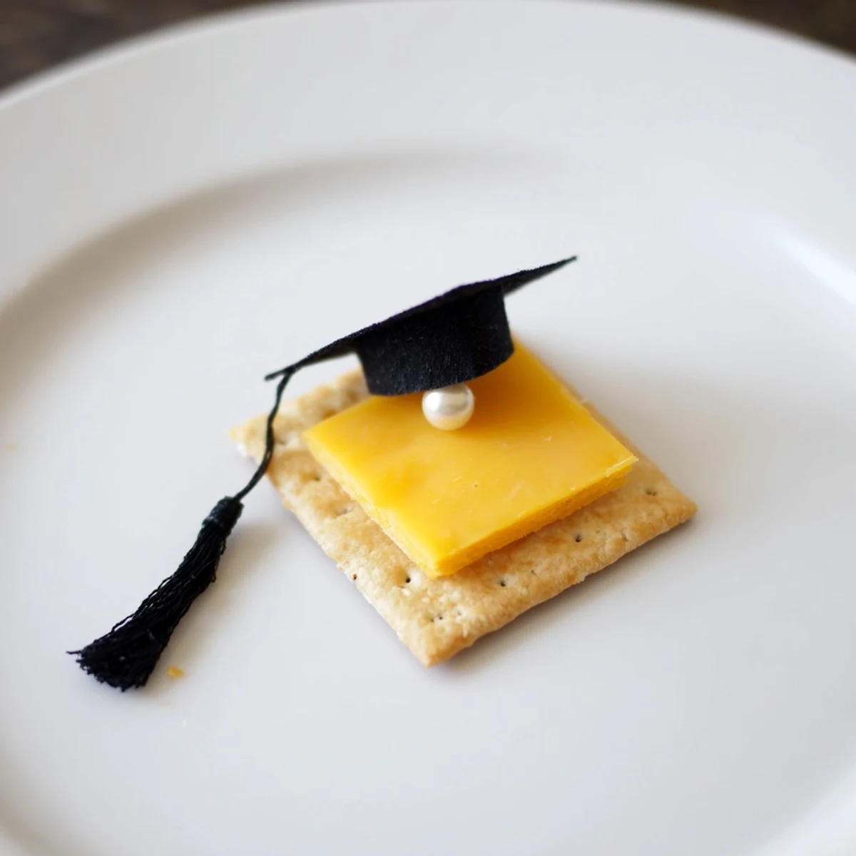 Close-up of whimsical Graduation Cap Snacks with cream cheese "glue" holding the licorice tassels.