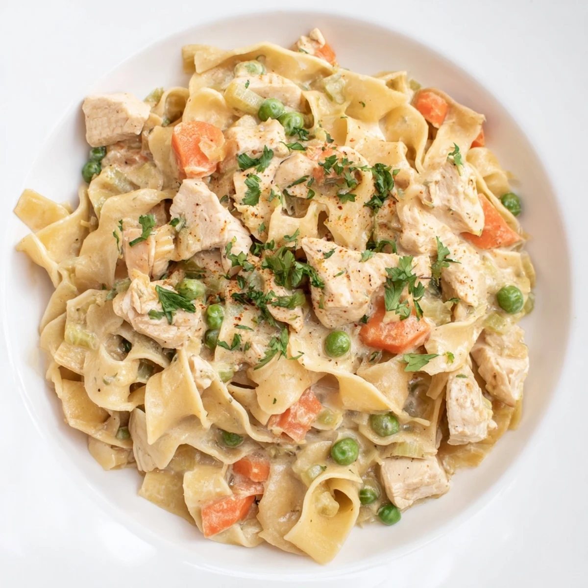 Delicious bowl of creamy chicken and egg noodles, garnished with fresh parsley, ready to eat.