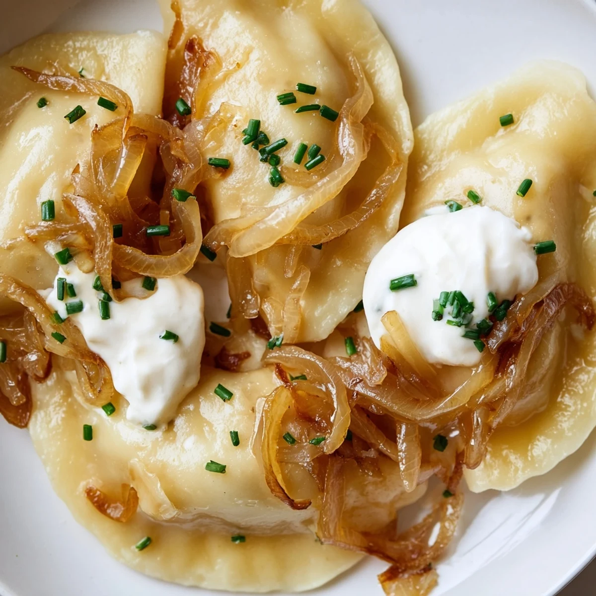 Golden, pan-fried Polish pierogi dumplings filled with cheesy potato, served with sweet onions.