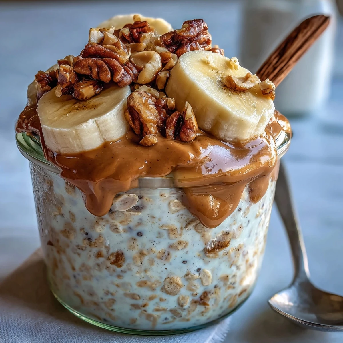 Thick overnight oats topped with fresh blueberries and a peanut butter swirl on a white plate.