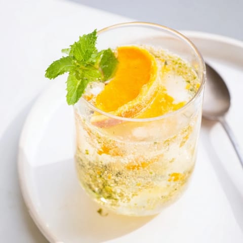 Homemade probiotic soda mocktail served over ice, garnished with vibrant orange slices.  