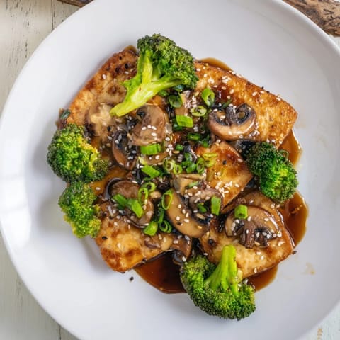 A plate of flavorful sautéed tofu steak, perfectly cooked with a savory soy-garlic sauce.