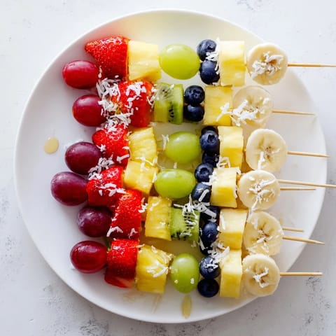 A colorful serving of Easy Festive Fruit Kabobs, featuring juicy pineapple with sweet blueberries and kiwi.