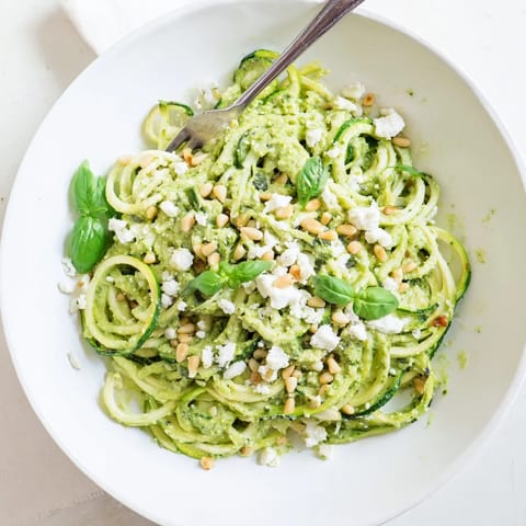 Creamy avocado pesto coats tender zucchini noodles in this healthy, low-carb meal served with toasted pine nuts.