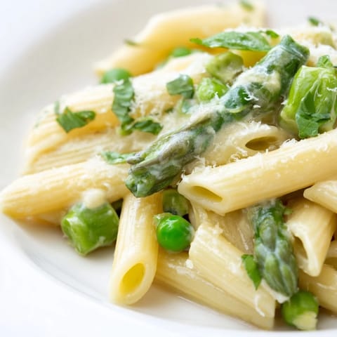 A close-up of creamy Garlic Parmesan Spring Vegetable Pasta, featuring al dente penne, vibrant spring vegetables, and a glossy, light sauce ready to serve.