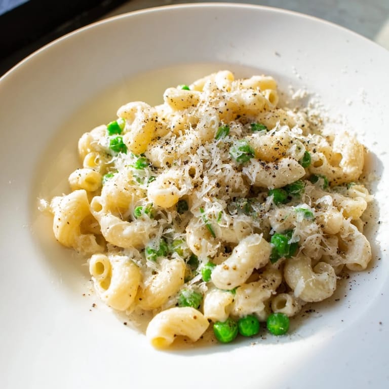 Close-up of golden macaroni & peas tossed with Parmesan cheese, ready to eat.