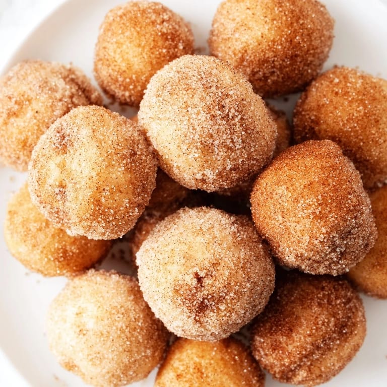 A close-up of delicious, miniature Air Fryer Cinnamon Donuts, coated and ready to eat fresh.